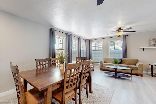 dining area with light wood-style floors, ceiling fan, baseboards, and plenty of natural light