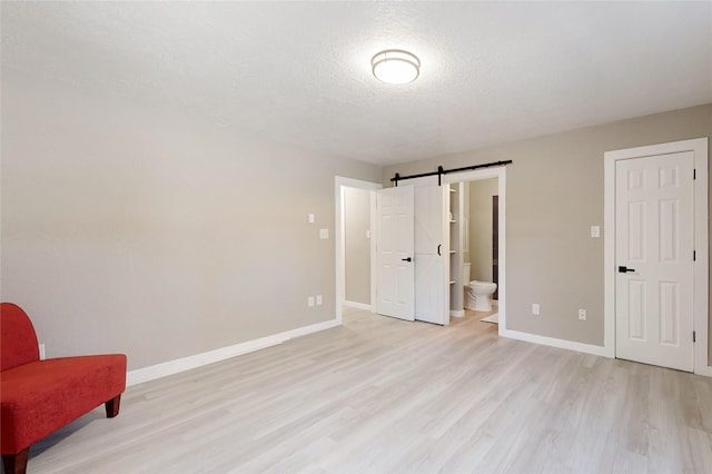 bedroom featuring light wood-style flooring, a barn door, and baseboards