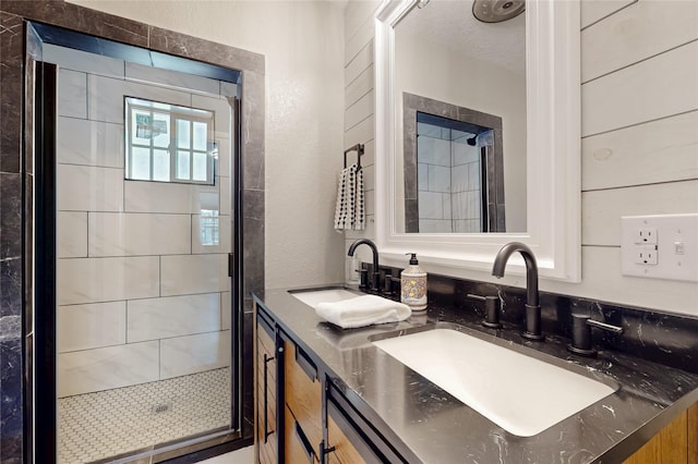 full bath featuring a stall shower, double vanity, and a sink