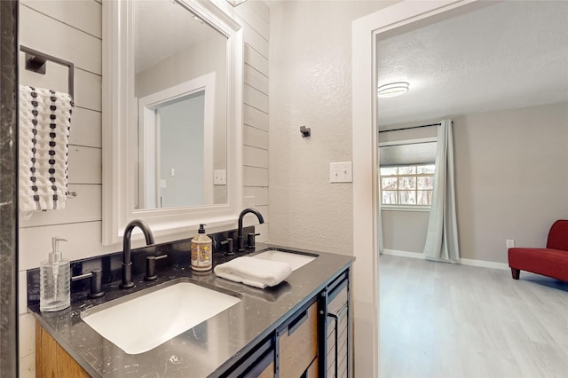 bathroom featuring a sink, baseboards, double vanity, and wood finished floors