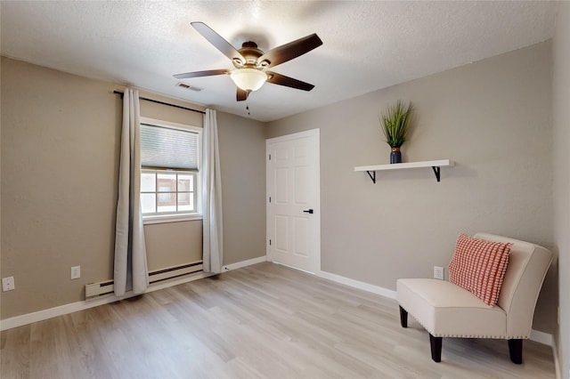 sitting room featuring light wood-style floors, ceiling fan, baseboards, and visible vents