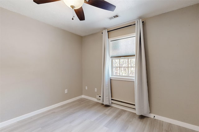 spare room with visible vents, baseboards, a baseboard radiator, light wood-type flooring, and a ceiling fan
