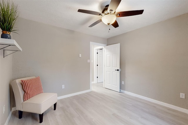 sitting room featuring baseboards, light wood-type flooring, and a ceiling fan