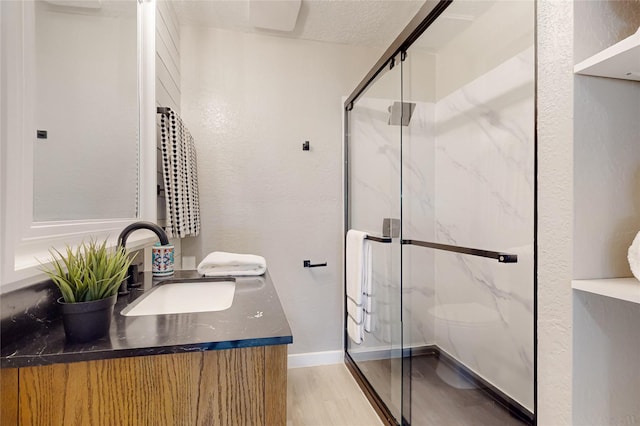 full bathroom featuring vanity, a marble finish shower, and wood finished floors