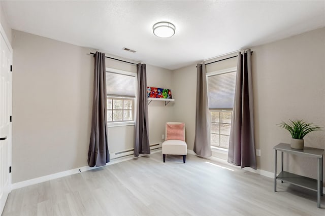 sitting room featuring light wood-style flooring, a baseboard radiator, baseboards, and visible vents
