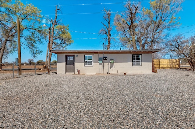 rear view of property with stucco siding, fence, and a gate