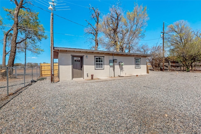 back of house with an outbuilding, fence, and stucco siding