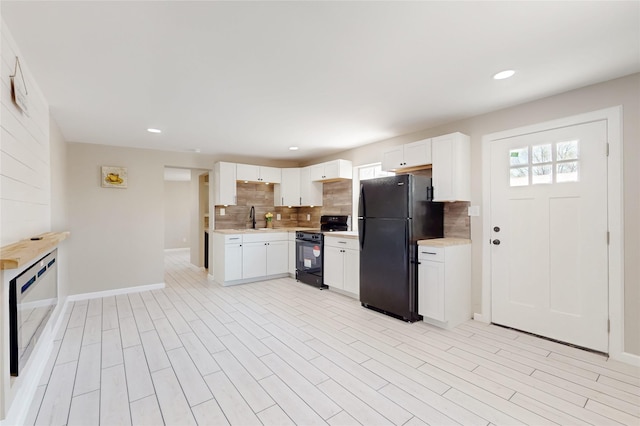 kitchen with tasteful backsplash, baseboards, light countertops, black appliances, and a sink