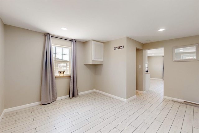 spare room featuring recessed lighting, light wood-type flooring, and baseboards