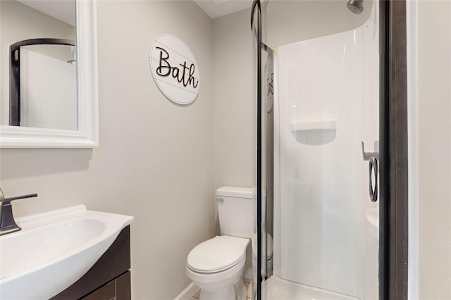 full bathroom with toilet, a stall shower, baseboards, and vanity