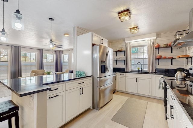 kitchen with dark countertops, light wood-style floors, open shelves, and stainless steel fridge
