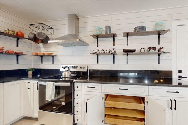 kitchen featuring wooden walls, open shelves, wall chimney exhaust hood, and stainless steel range with electric cooktop