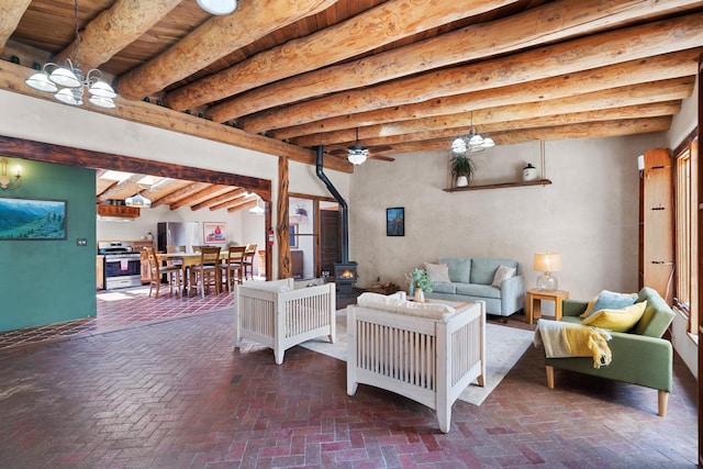 living area featuring brick floor, a wood stove, a ceiling fan, and beam ceiling