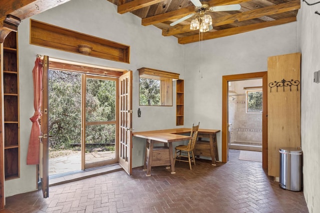 office area with beamed ceiling, brick floor, a ceiling fan, and wooden ceiling