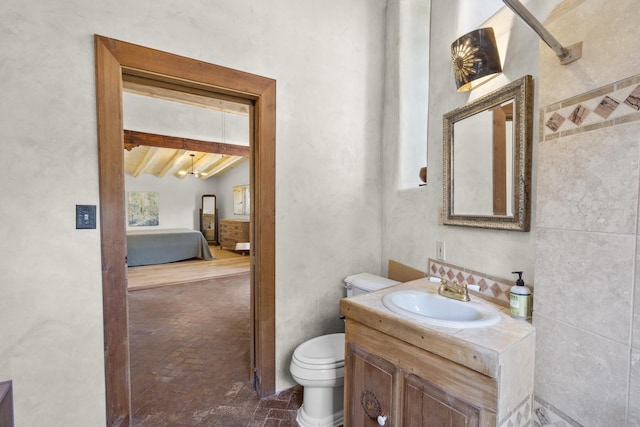 bathroom with vanity, toilet, and lofted ceiling with beams