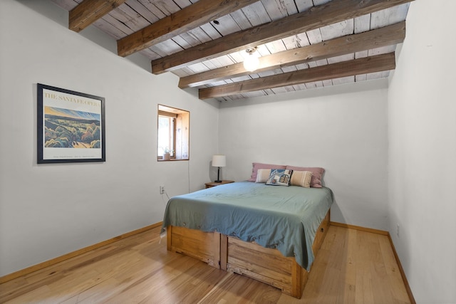 bedroom with beamed ceiling, baseboards, wooden ceiling, and wood finished floors