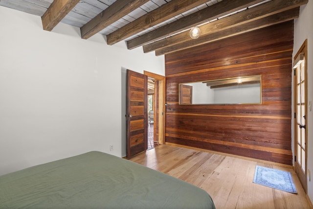 bedroom featuring wood walls, wooden ceiling, beamed ceiling, and wood finished floors