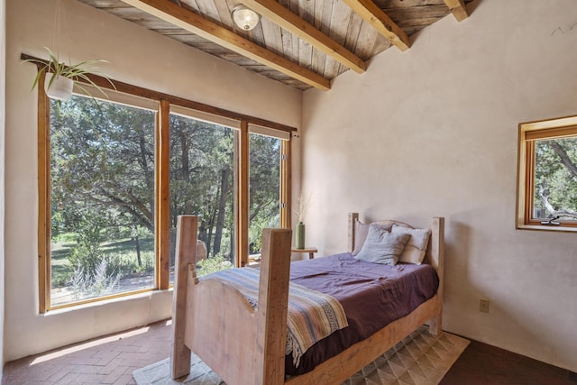 bedroom with beamed ceiling, brick floor, and wooden ceiling