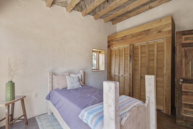 bedroom featuring brick floor, beamed ceiling, and multiple closets