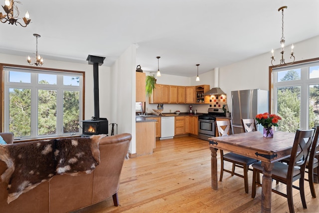 dining space with a chandelier, a wood stove, and light wood finished floors
