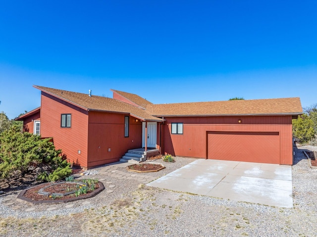 ranch-style home with a garage, driveway, and a shingled roof