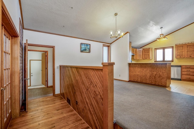 hallway featuring a notable chandelier, vaulted ceiling, ornamental molding, a textured ceiling, and visible vents