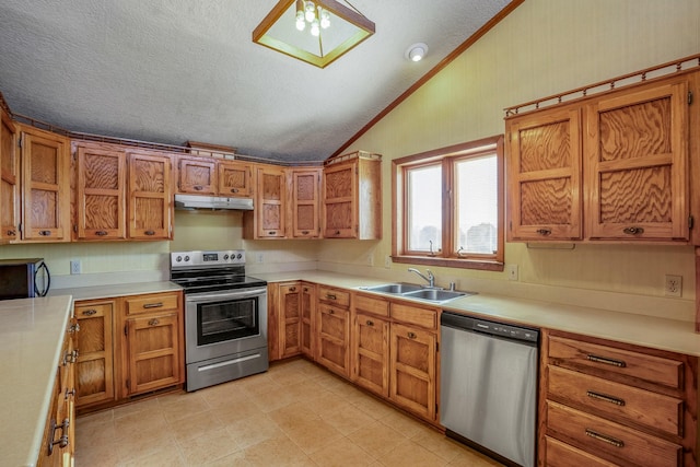 kitchen with a sink, under cabinet range hood, brown cabinets, lofted ceiling with skylight, and stainless steel appliances