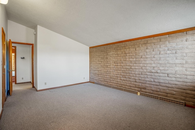 spare room featuring a textured ceiling, carpet flooring, lofted ceiling, brick wall, and baseboards