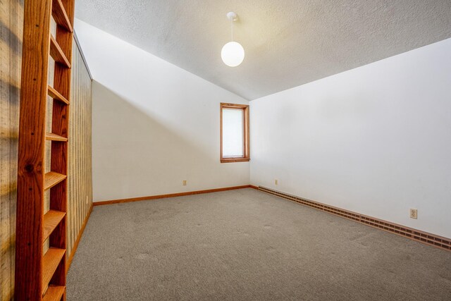 spare room with baseboards, carpet, a textured ceiling, vaulted ceiling, and a baseboard heating unit