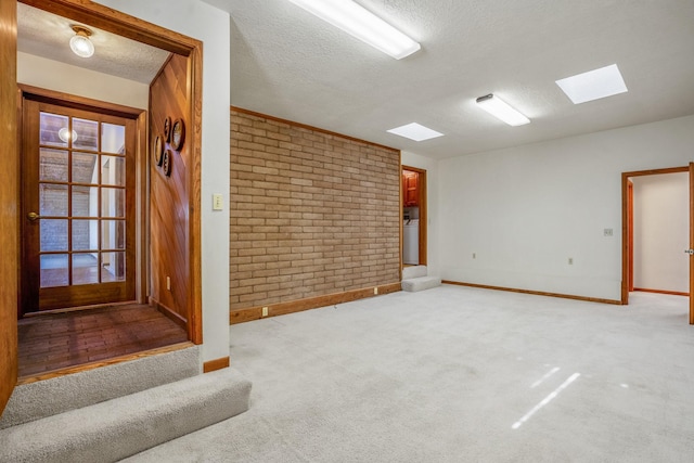 unfurnished room with baseboards, light colored carpet, brick wall, and a textured ceiling