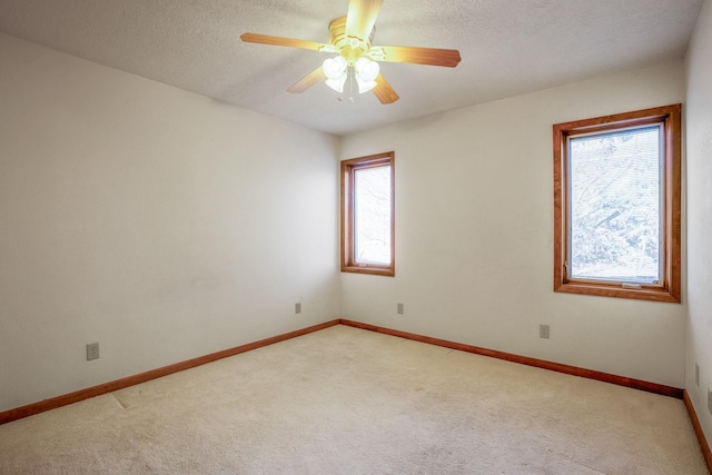unfurnished room featuring light colored carpet, baseboards, a ceiling fan, and a textured ceiling