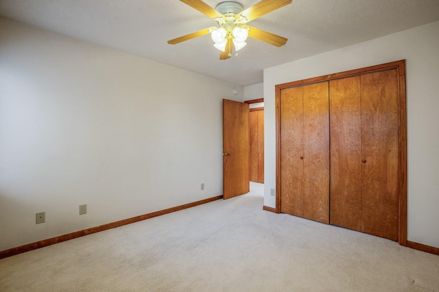 unfurnished bedroom featuring light carpet, a closet, ceiling fan, and baseboards