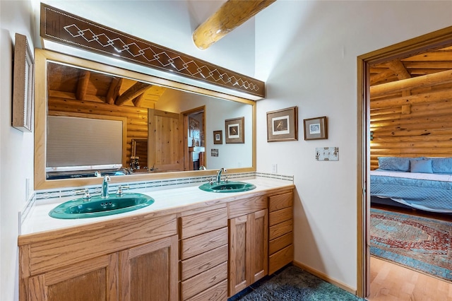 387 County Road B64, Pecos, NM 87552 - bathroom with log walls, double vanity, beam ceiling, baseboards, and connected bathroom