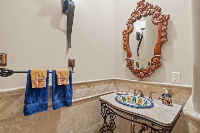 bathroom featuring a sink, wainscoting, and tile walls