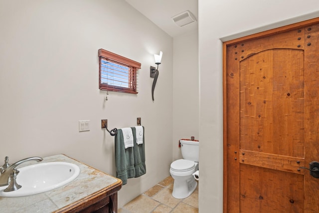 bathroom featuring toilet, stone finish floor, vanity, and visible vents