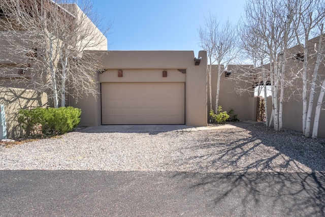 view of side of property with stucco siding, a garage, and gravel driveway