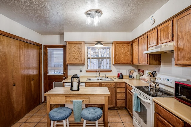 kitchen with under cabinet range hood, light tile patterned floors, a sink, and white electric stove