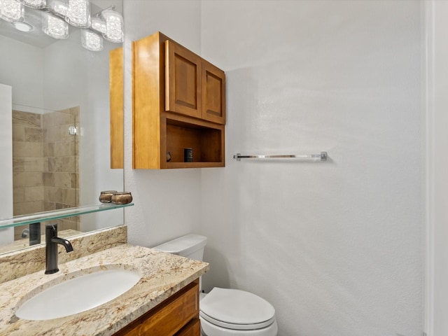 bathroom featuring toilet, vanity, and a tile shower