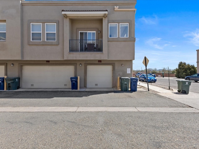 back of property with a garage and stucco siding