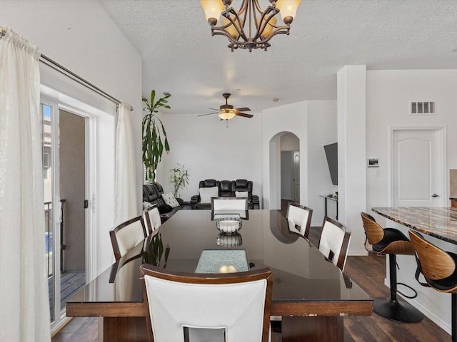 dining space featuring arched walkways, wood finished floors, a textured ceiling, a chandelier, and a ceiling fan