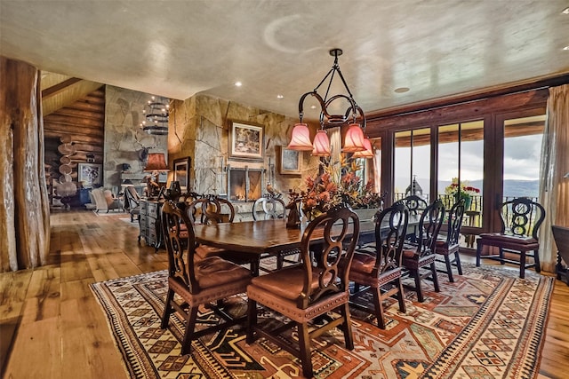 dining space featuring hardwood / wood-style floors, a chandelier, and rustic walls