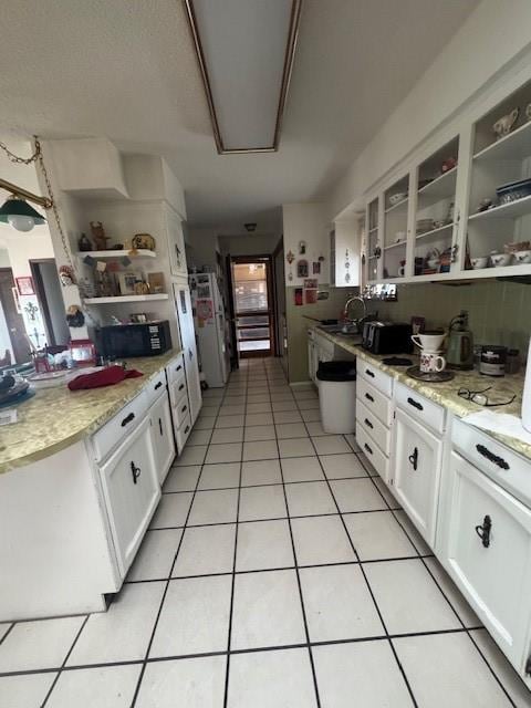 kitchen with open shelves, a sink, black microwave, light tile patterned floors, and white cabinetry