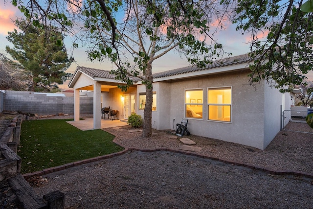 10335 Dunbar St NW, Albuquerque, NM 87114 - back of house featuring fence, a yard, stucco siding, a tile roof, and a patio