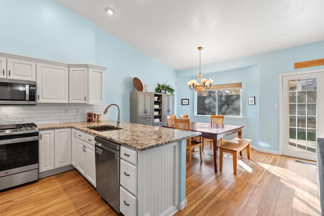 10335 Dunbar St NW, Albuquerque, NM 87114 - kitchen featuring a sink, decorative backsplash, a chandelier, stainless steel appliances, and a peninsula