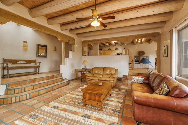 living area with tile patterned floors, a ceiling fan, beamed ceiling, wood ceiling, and stairs
