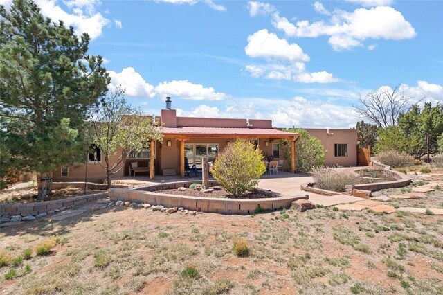 rear view of property featuring stucco siding, a chimney, and a patio area