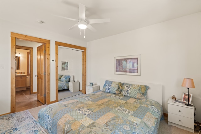 tiled bedroom with a ceiling fan, baseboards, a closet, and ensuite bathroom