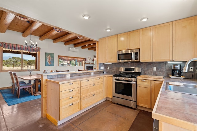 kitchen featuring a peninsula, light brown cabinets, a sink, and appliances with stainless steel finishes
