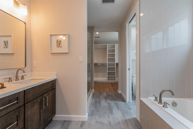 bathroom featuring a bath, a stall shower, baseboards, visible vents, and vanity