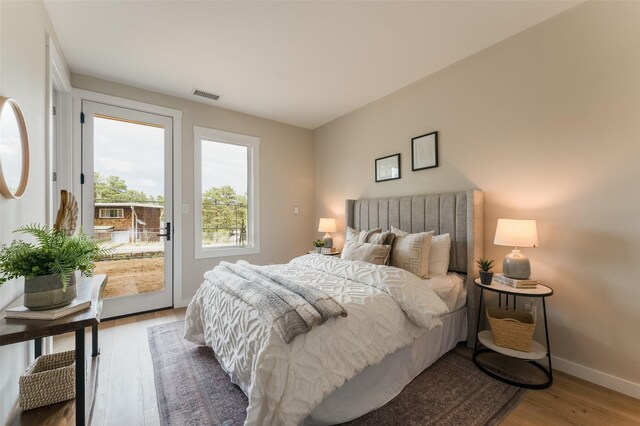 bedroom featuring baseboards, wood finished floors, visible vents, and access to outside